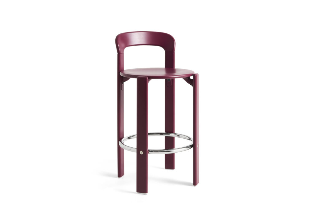 Tabouret haut moderne Rey de couleur bordeaux avec un dossier incurvé, une assise ronde, quatre pieds droits et un repose-pieds circulaire chromé, le tout sur un fond blanc uni.