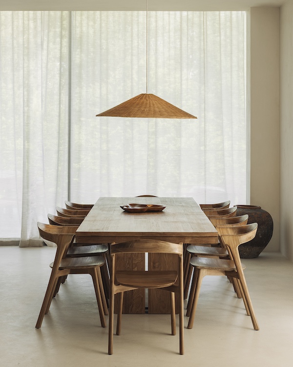 Une salle à manger minimaliste avec une table en bois, huit chaises assorties et une lampe suspendue conique évoque l'élégance du design quatuor - une inspiration parfaite pour tout magasin de meubles design.