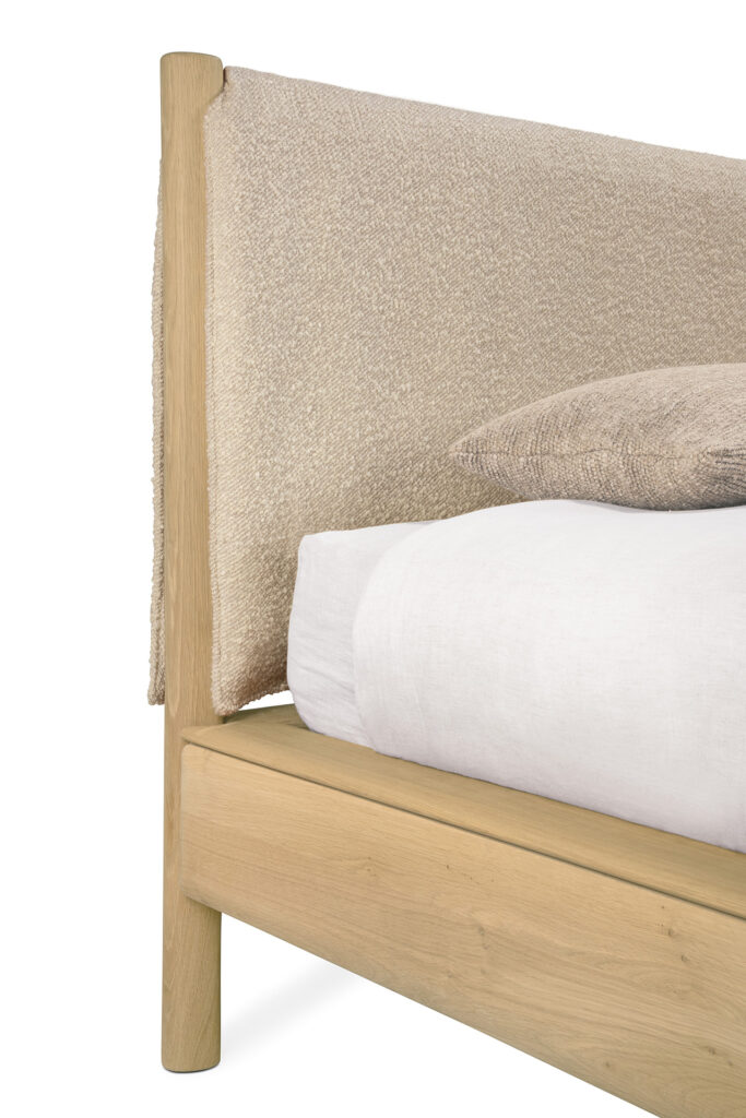 Gros plan d'un lit PI au format 160x200, composé d'un cadre en bois, d'une tête de lit en tissu texturé beige, d'une literie blanche douce et d'un oreiller beige en forme de nuage.