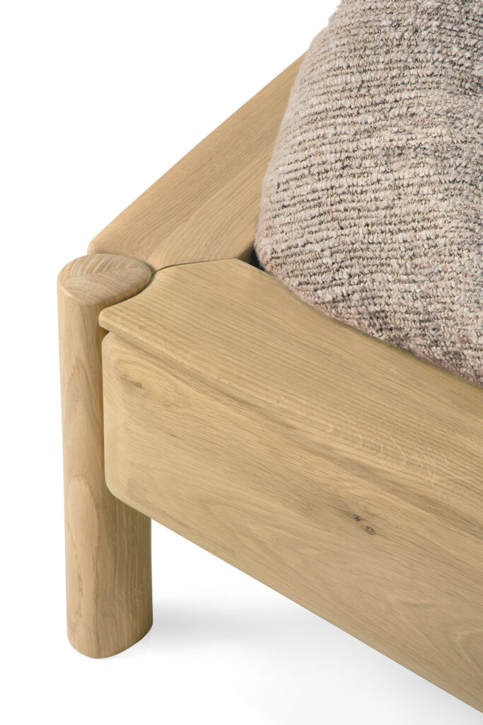 Gros plan sur un coin de cadre de lit PI aux pieds arrondis, conçu en 160x200, recouvert d'une couverture ou d'un coussin beige texturé créant une sensation de confort et de nuage.