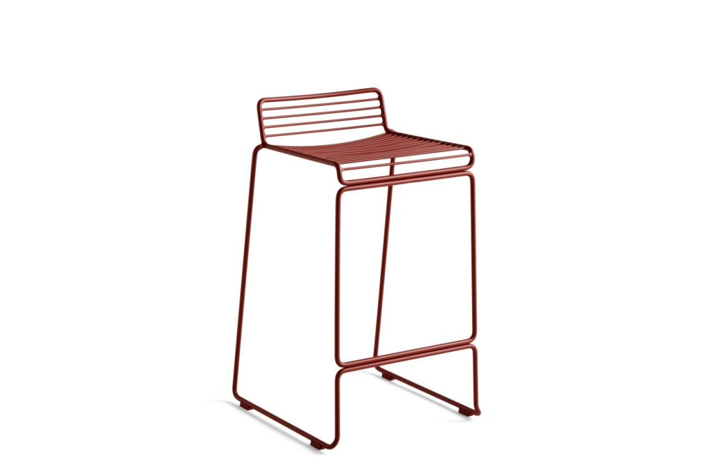 Tabouret design Tabouret Hee en métal rouge, avec assise et dossier à lattes, doté d'un cadre géométrique minimaliste - une pièce emblématique du mobilier moderne sur fond blanc.