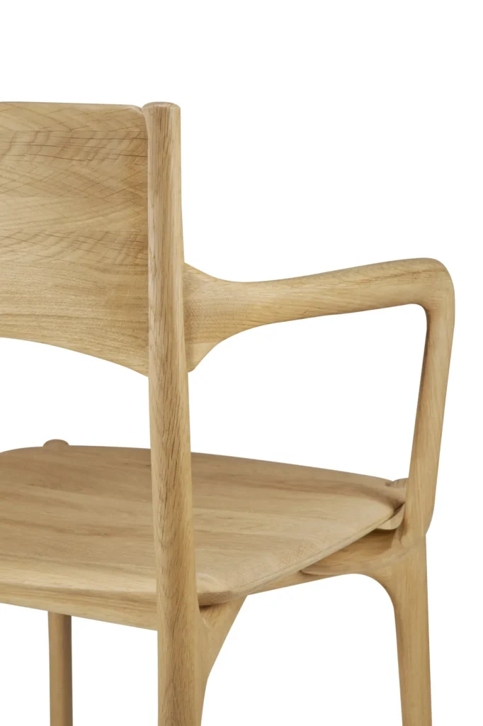 Gros plan sur une chaise PI moderne en bois, avec un dossier incurvé, des accoudoirs en angle et une finition lisse en chêne naturel.