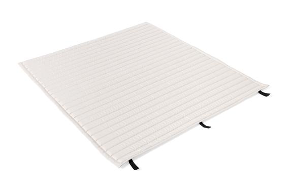 Un coussin blanc crème, rectangulaire, matelassé, avec des coutures horizontales et des boucles de tissu noir sur les côtés, posé à plat sur un fond blanc.