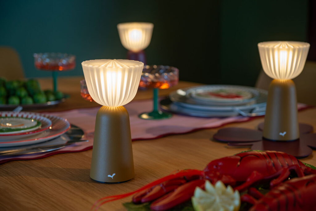 Gros plan sur une table à manger composée d'assiettes, de verres, de homards artificiels et de lampes de table modernes Lampe Swiing diffusant une lumière chaude, idéale pour déguster un pain d'épices.