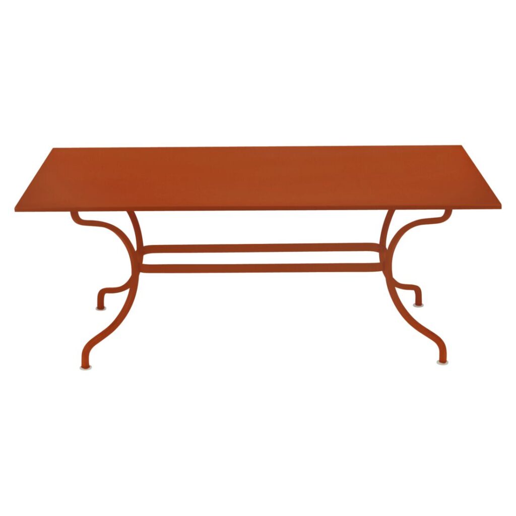 La table Romane présente un plateau rectangulaire en métal orange avec des pieds incurvés et une barre de soutien reliant les pieds en dessous, rappelant le charme vibrant d'Orange Confite.